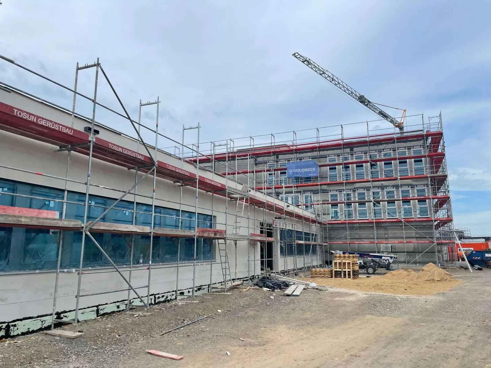 Gewerbeneubau in Limburg mit umlaufendem Fassadengerüst und Baukran